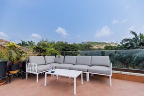 A rooftop terrace with a grey sectional sofa, a white coffee table, and potted plants. - Garden loft 302 (Adenta Municipality)