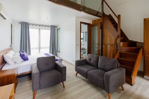 A modern hotel room with a bed, two armchairs, a sofa, a wooden staircase, and a bathroom visible through an open door. - Garden loft 302 (Adenta Municipality)