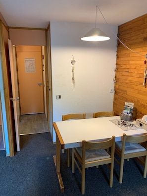 Un espace repas comprenant une table, des chaises, un luminaire suspendu, un élément décoratif fixé au mur et un mur en bois.