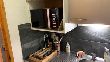 A kitchen with a microwave, a toaster, a sink, and various utensils.