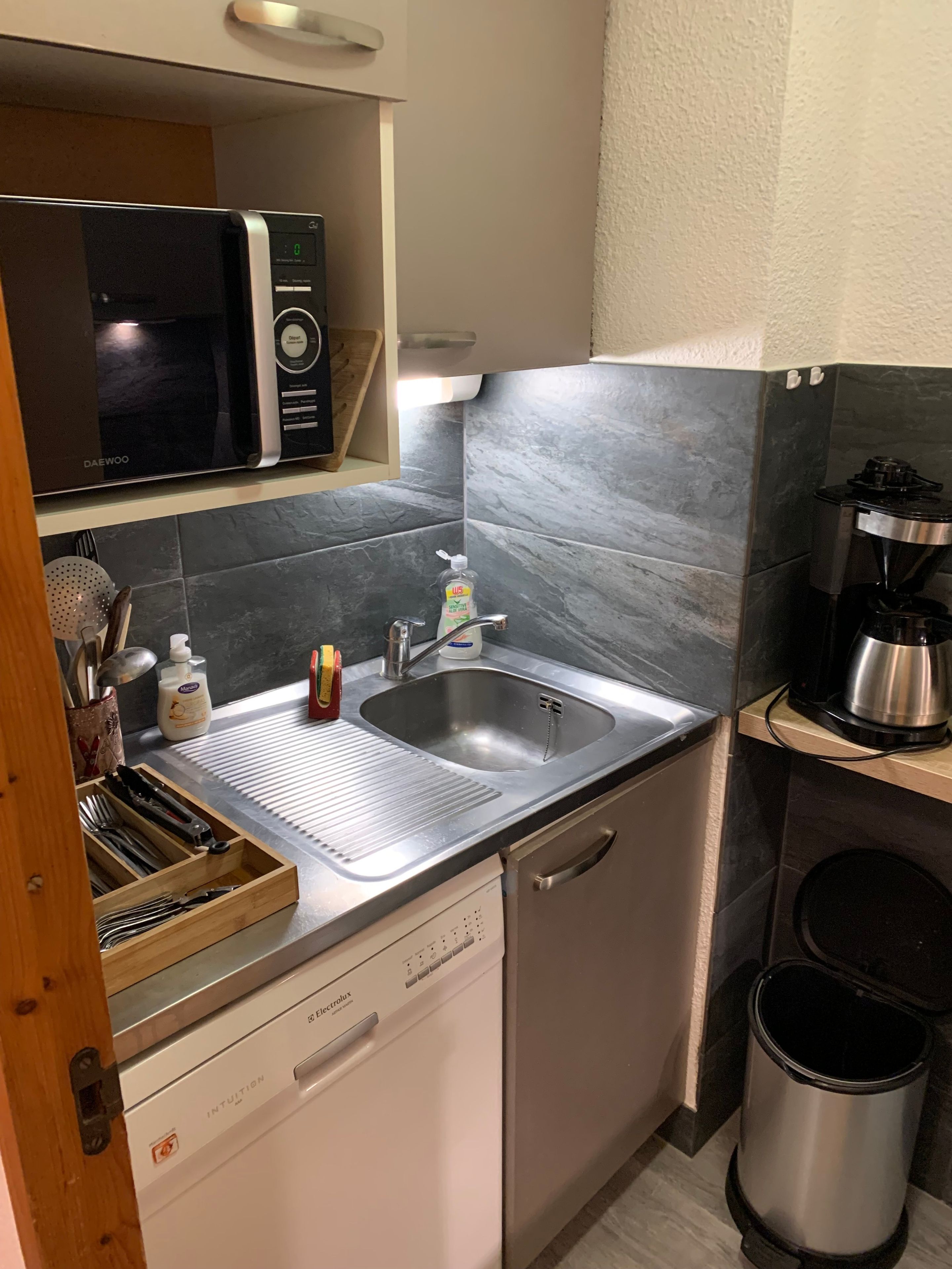 A compact kitchen with a microwave, sink, and dishwasher.