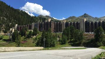 Ein mehrstöckiges Hotel mit moderner Architektur, eingebettet in eine bewaldete Berglandschaft unter blauem Himmel.