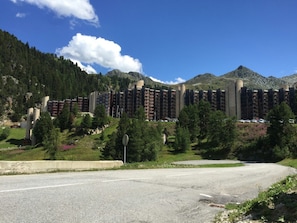 Un hôtel à plusieurs étages, doté d’une architecture moderne, situé dans une région montagneuse, au cœur d’une végétation luxuriante, sous un ciel bleu azur.