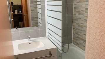 A modern bathroom with a glass-enclosed shower, a white sink, and a mirror.