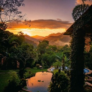 A lush landscape with a pond, trees, and a view of distant mountains during sunset. - New Listing (Paraty)