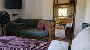 A room with a sofa, a bed, a fan, and a view of a kitchen area. - New Listing (Paraty)