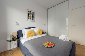 A neatly arranged bedroom with a bed, bedside tables, a wardrobe, and a painting on the wall. - Wola Flat with Free Parking (Warszawa)