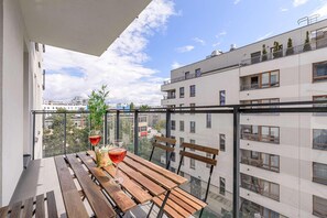 A balcony with a wooden table, two chairs, and a potted plant. - Wola Flat with Free Parking (Warszawa)