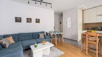 Un soggiorno moderno con un divano blu, un tavolino da caffè bianco e un'area pranzo con tavolo e sedie.