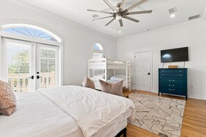 A bedroom with a bed, bunk beds, a ceiling fan, a television, and a dresser. - Welcome to Soleil House, a  Seacrest Beach retreat perfectly located on 30A. (Seacrest)