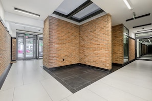 A modern interior with brick walls, a tiled floor, and a glass door entrance. - Apartment near River Walks (Warszawa 2)