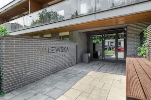 A modern building entrance with a brick wall and glass doors, labeled 'WALeWSKA residence.' - Apartment near River Walks (Warszawa 2)