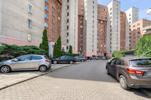 Un espace de stationnement où sont garées de nombreuses voitures, entouré d’immeubles résidentiels de grande hauteur, tous dotés d’un style architectural uniforme.