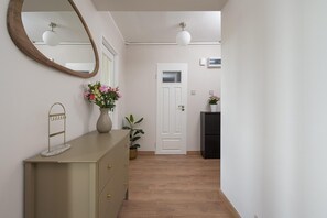 Um corredor com cômoda, espelho, porta e uma pequena planta.