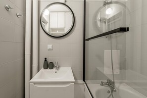 Un baño con lavabo, espejo y ducha.