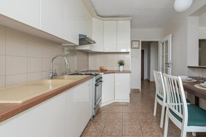 Eine moderne Küche mit weißen Schränken, einer Holz Arbeitsplatte, einer Spüle und einem Herd.
