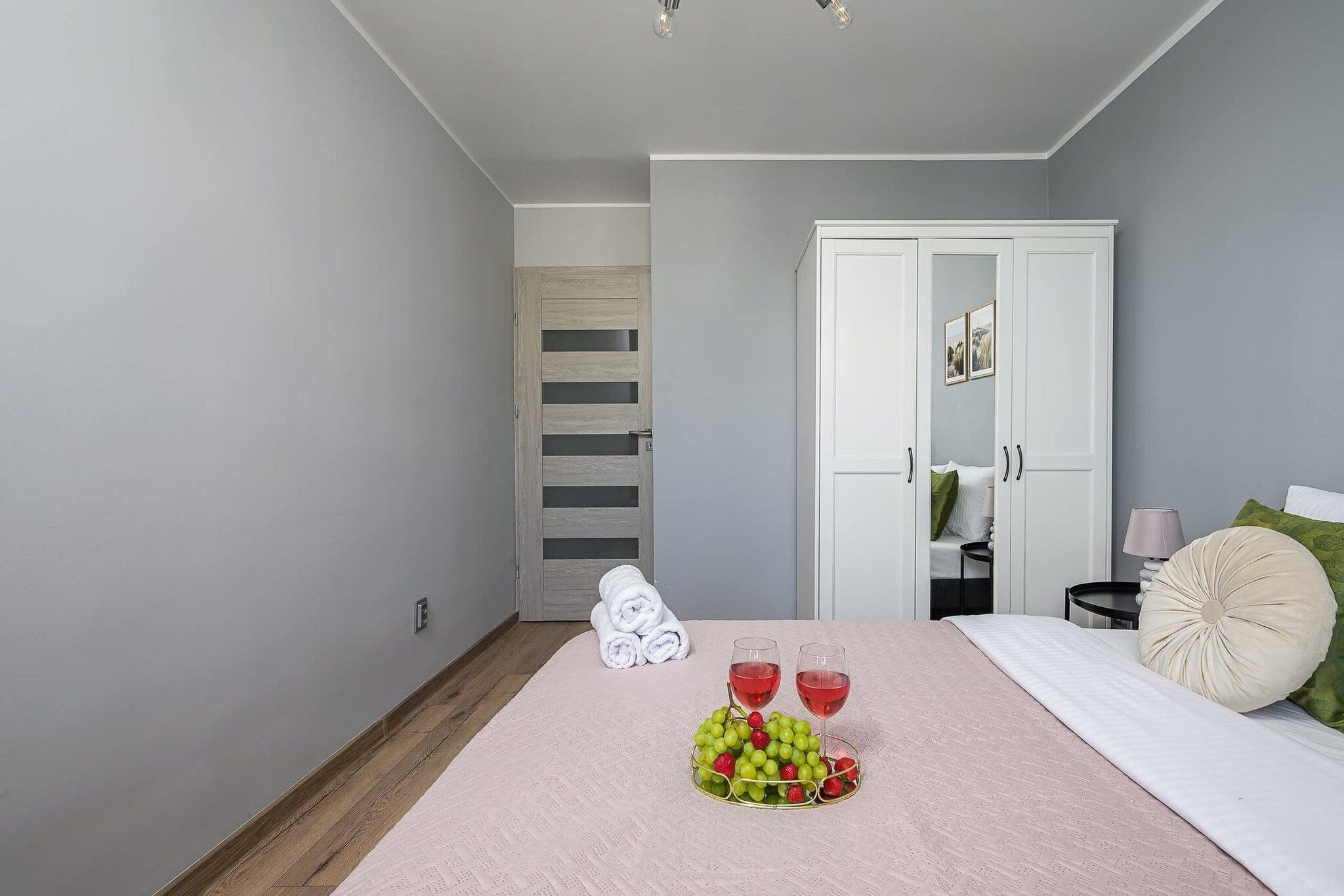 Une chambre à coucher avec un lit, une table de chevet, une lampe et une porte donnant sur une autre pièce.