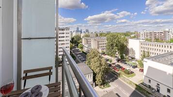 Ein Balkon mit Tisch, Stühlen und einem Glas Rotwein.