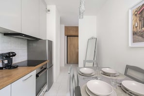 A modern kitchen with a Bosch coffee maker, a stand-up mixer, and a dining area with white plates and glasses. - Retreat by Park Skaryszewski (Warszawa)