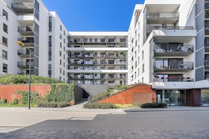 A modern multi-story residential building with balconies, a paved courtyard, and a staircase leading to the entrance. - Retreat by Park Skaryszewski (Warszawa)