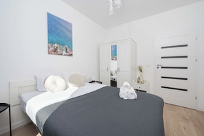 A bedroom with a bed, pillows, a bedside table, a mirror, a wardrobe, and a painting on the wall. - Retreat by Park Skaryszewski (Warszawa)