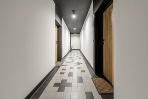 A hallway with a checkered floor pattern, a bicycle, and a door with a textured surface. - Retreat by Park Skaryszewski (Warszawa)