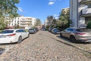 Une rue pavée bordée de voitures garées et d’immeubles à plusieurs étages.