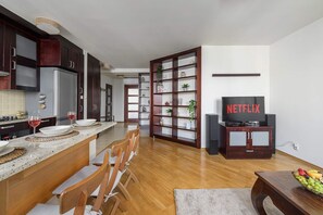 A modern kitchen with a dining area, a bookshelf, and a television labeled 'NETFLIX'. - Urban Oasis with Balcony near Zoo (Warszawa)