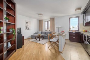 A modern living room with a sofa, dining table, and a kitchen area with a window. - Urban Oasis with Balcony near Zoo (Warszawa)