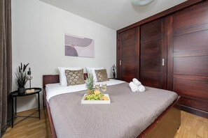 Une chambre d’hôtel comprenant un lit, une table de chevet, une œuvre d’art murale et une grande armoire.