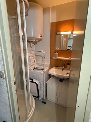 Une petite salle de bain comprenant un lavabo, un miroir et un espace douche.