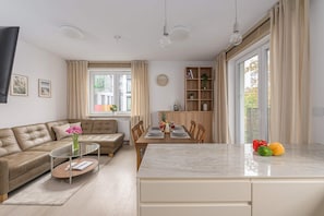 A modern living room with a sofa, coffee table, and dining area with a table set for two. - Large Flat with Courtyard (Warszawa)