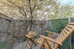 A patio with a metal fence, a wooden table with a glass of wine, and two wooden chairs. - Large Flat with Courtyard (Warszawa)