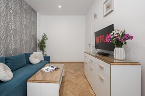 Un salon moderne comprenant un canapé, une table basse, un téléviseur et un vase décoratif.