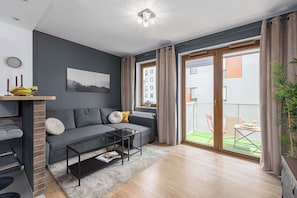 A modern living room with a grey sofa, a coffee table, and a view of a balcony with outdoor furniture. - Central Apartment near Museums (Warszawa)