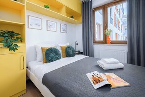 Ein modernes Schlafzimmer mit einem Bett, Kissen, einer Zeitschrift und einem Fenster mit Vorhängen.