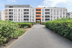 A multi-story residential building with a central entrance, surrounded by well-maintained hedges. - Central Apartment near Museums (Warszawa)