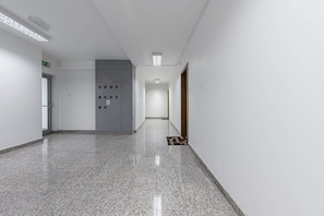 A corridor with a grey utility panel, a door, and a tiled floor. - Saska Apartment near Old Town (Warszawa)