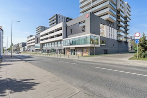A modern multi-story building with balconies, a clear sky, and a pedestrian crossing. - Central Flat near Manufaktura (Łódź)