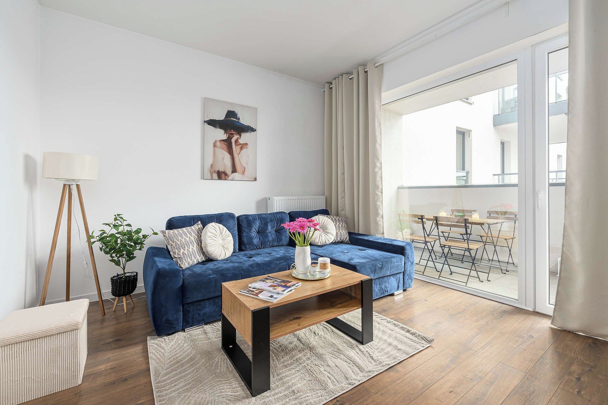 Een moderne woonkamer met een blauwe bank, een houten bijzettafeltje en een vloerlamp.