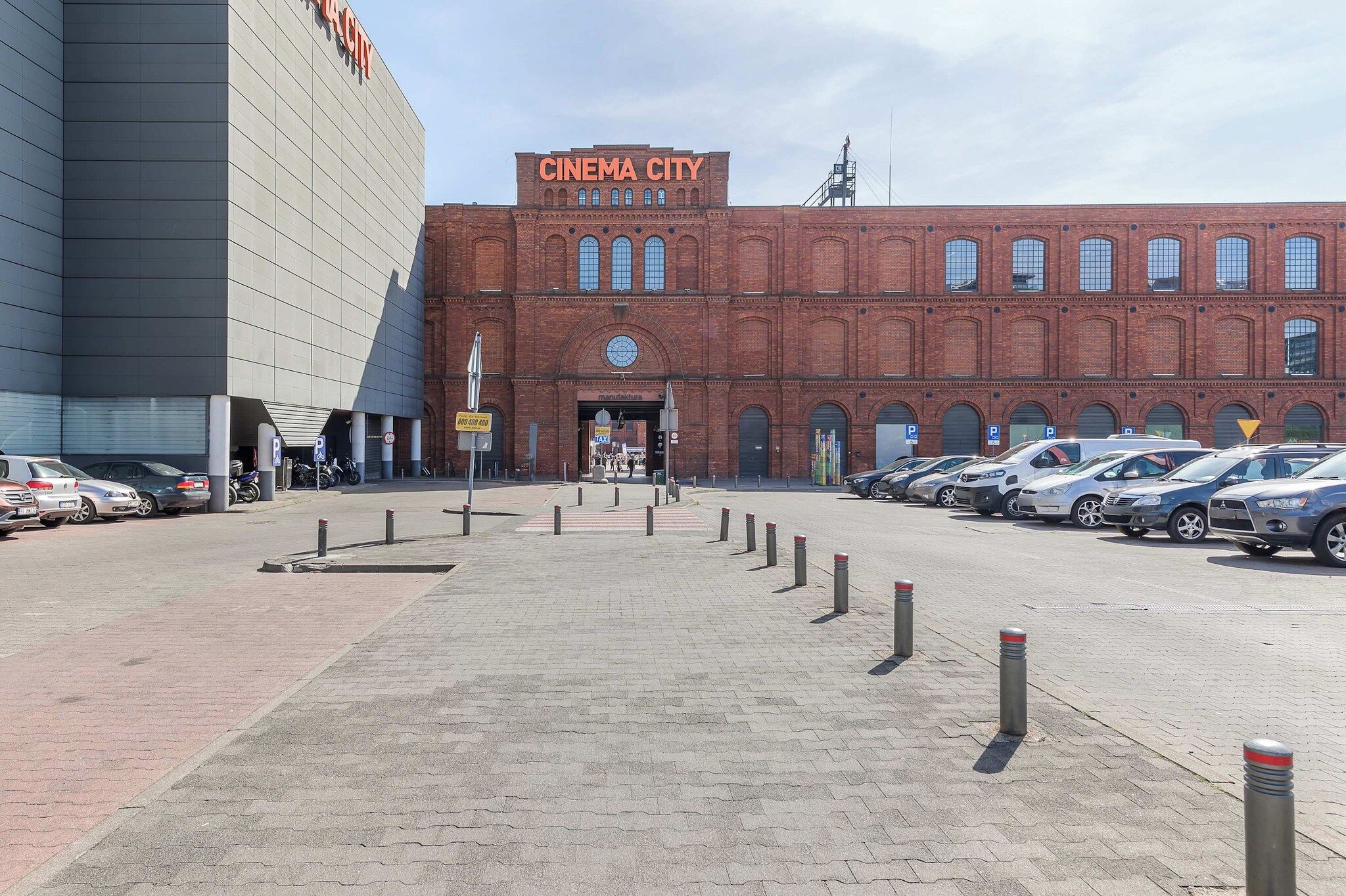 A parking lot with cars, a building labeled 'CINEMA CITY,' and a brick entrance.