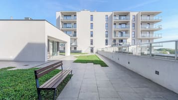 A modern apartment building with a central courtyard, a bench, and a glass railing.