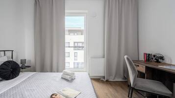 Een moderne slaapkamer met een bed, een bureau en uitzicht op een gebouw.