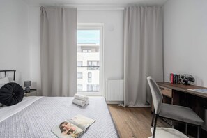 Een moderne slaapkamer met een bed, een bureau en uitzicht op een gebouw.