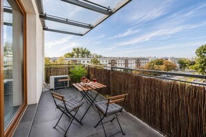 A balcony with a table and chairs, a wooden fence, and a view of buildings. - Apartment near Old Town (Warszawa)