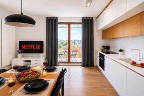 A modern apartment with a dining area, kitchen, and a balcony with curtains. - Apartment near Old Town (Warszawa)