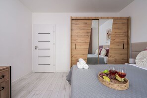 A bedroom with a bed, a wooden wardrobe, a white door, and a wall-mounted mirror. - Central Apartment with Terrace (Łódź)