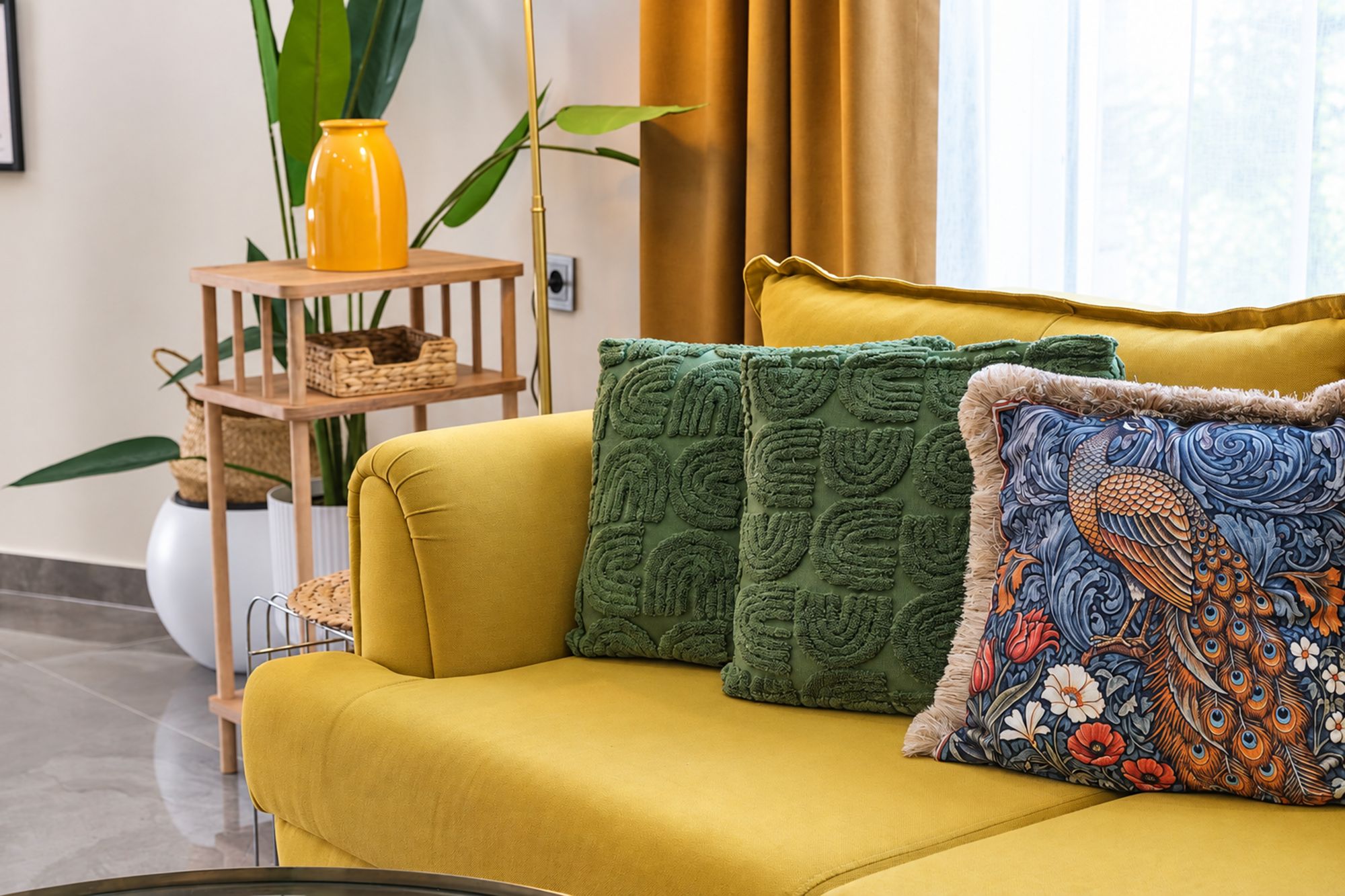 A yellow sofa with decorative pillows and a small wooden side table with a yellow vase and a woven basket.
