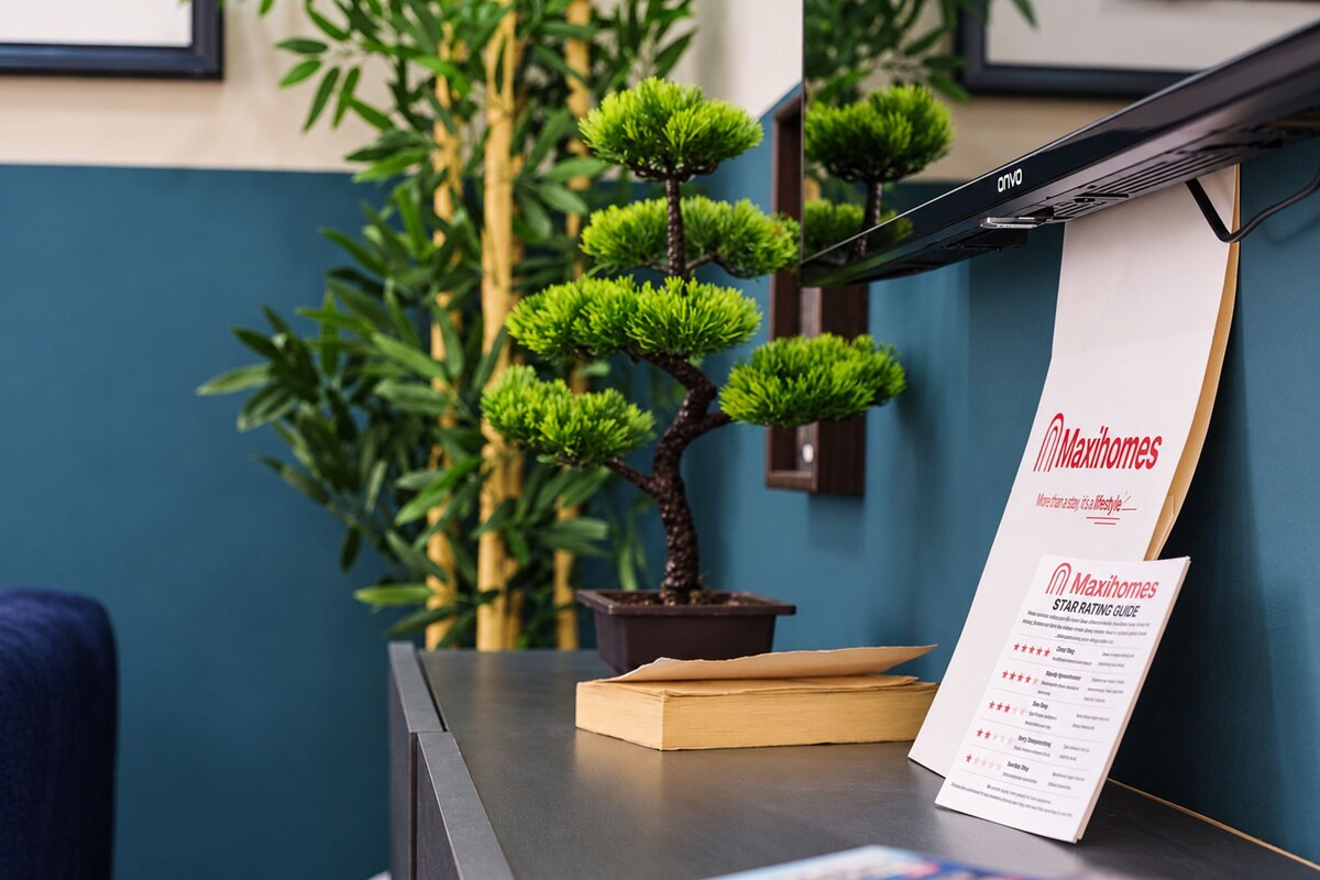 A reception desk with a framed picture, a potted plant, and a Maxihomes STAR RATING GUIDE.