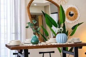 A dining table with white plates, a green vase, and a blue vase with flowers. - Maxihomes Mythos Collection (Muratpaşa)